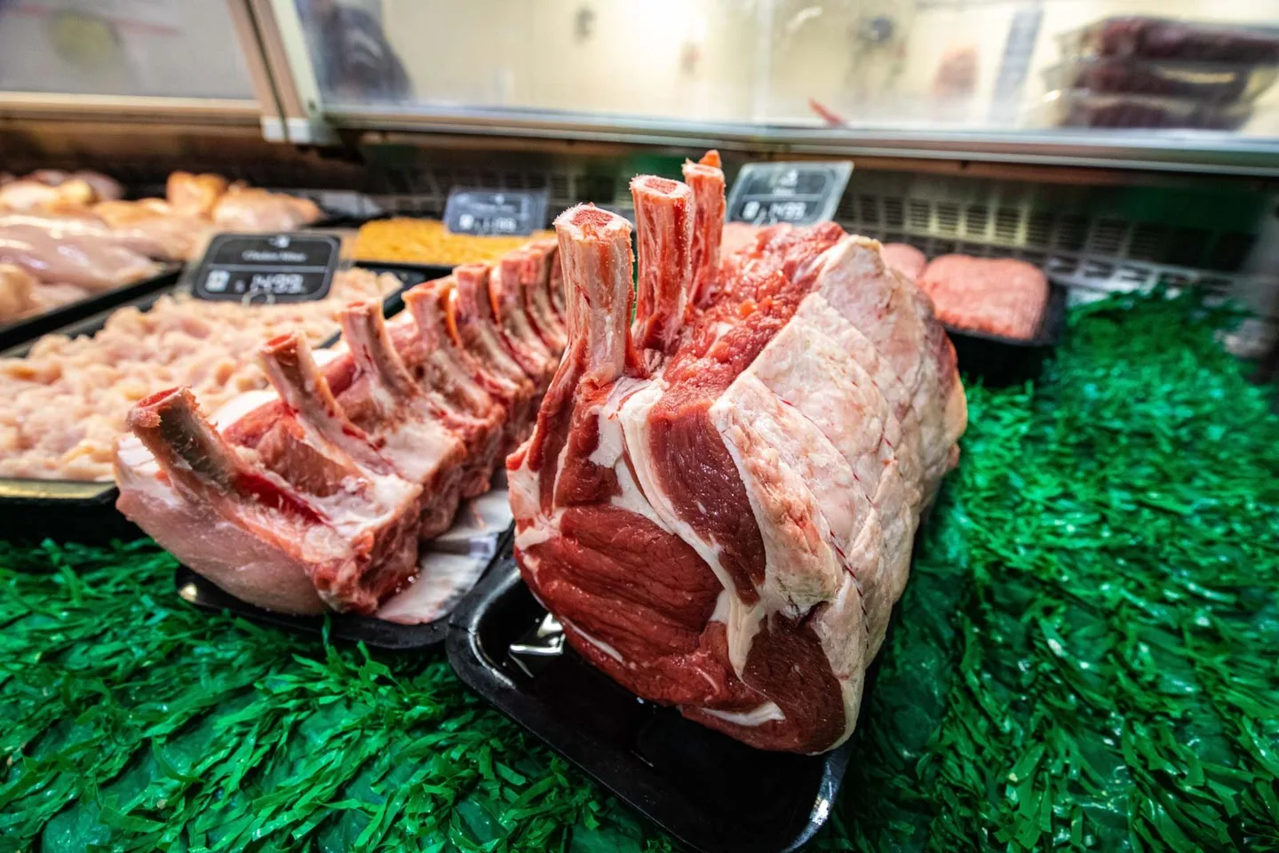 A trimmed rack of lamb on a tray in the butcher's display cabinet