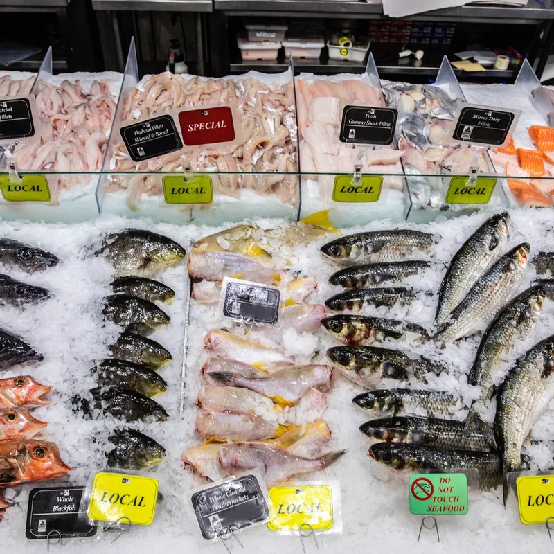 Whole local fish laid out on crushed ice behind the counter glass