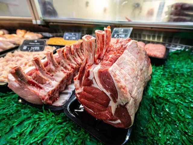 A rack of lamb and trimmed cuts on a tray in the butcher’s cabinet